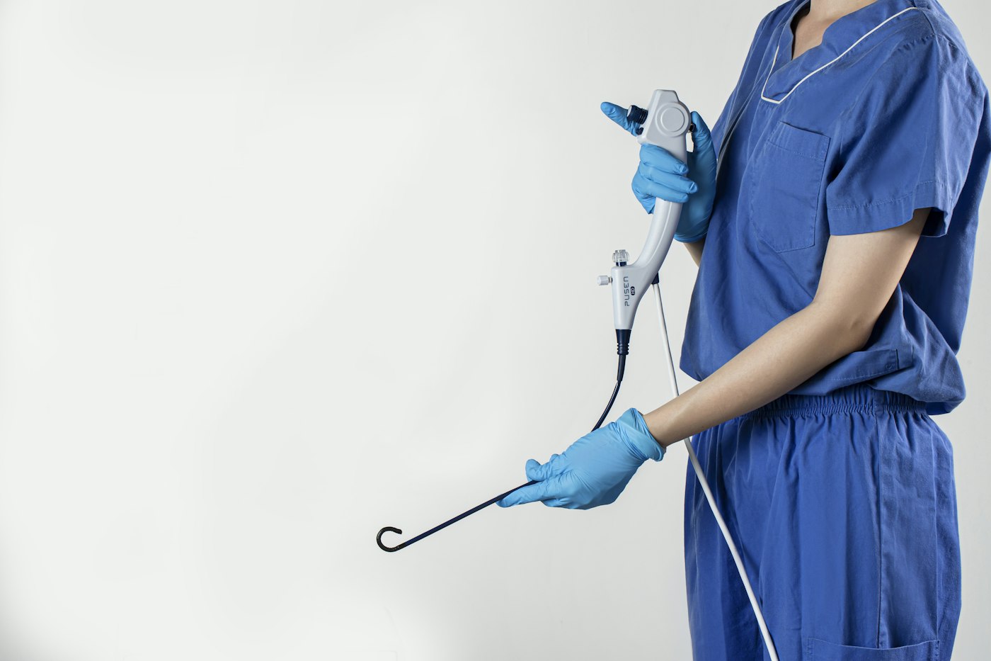 Clinician in blue scrubs holding a handheld medical instrument